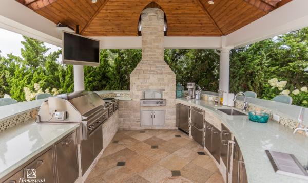 Full outdoor kitchen with pizza oven under pavilion.