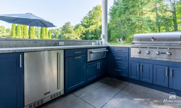 Outdoor kitchen with blue cabinets and grill.