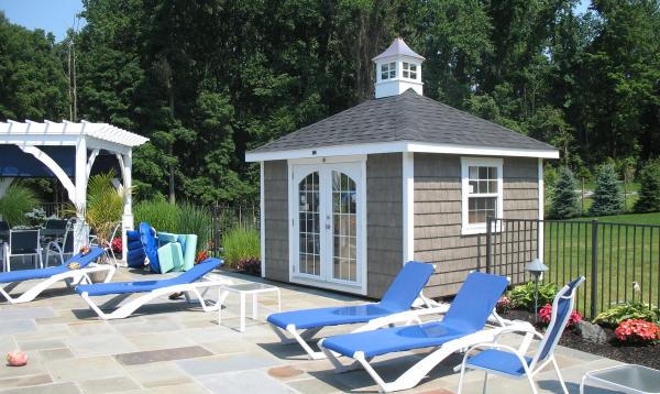 Pool shed from Homestead Structures next to chairs and pergola