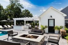 An outdoor patio with plants around a table and fire pit.