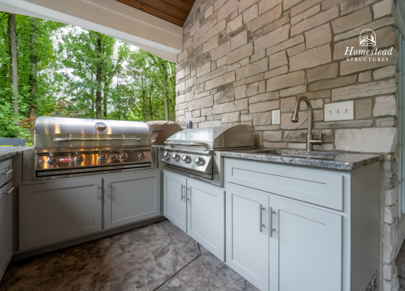 High-end outdoor kitchen featuring premium stainless-steel grills, granite countertops, modern cabinetry, and stonework, seamlessly blending convenience and style.