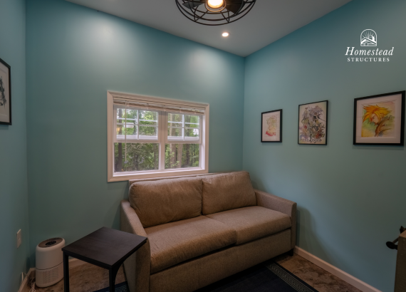 Cozy interior lounge area in a luxury pool house with light blue walls, modern sofa, artwork, and natural lighting, perfect for relaxing after pool time.