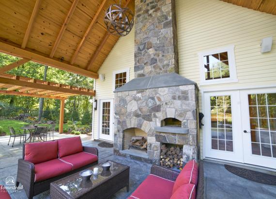 Exterior double-sided fireplace of 24' x 38' Custom Liberty Pool House in Wilton, CT