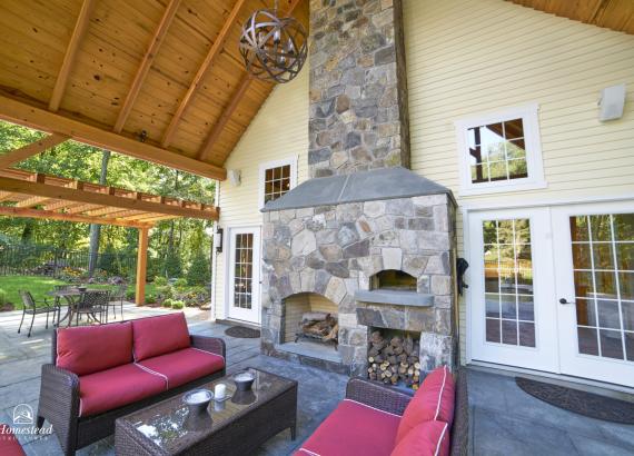 Exterior double-sided fireplace of 24' x 38' Custom Liberty Pool House in Wilton, CT