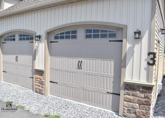 Arched Carriage Style Garage Doors, Porch Lights, Stone Veneer with Vinyl Board & Batten Siding on 3-Car Garage